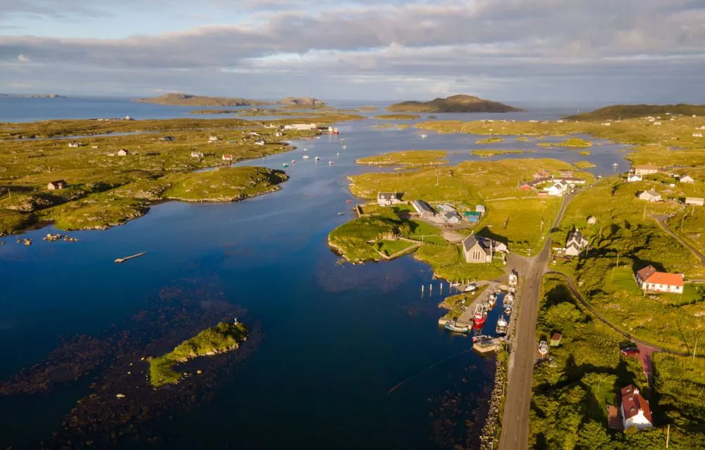 Aerial view of a rural coastal landscape with scattered islands, boats in the water, and buildings along the shoreline—a prime example of breathtaking sailing destinations.